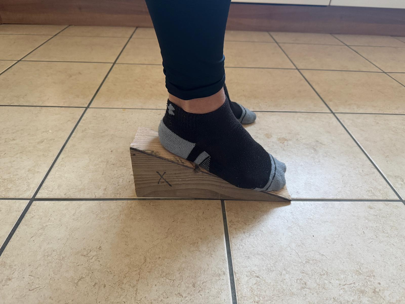 Home rehabilitation exercise, balancing the foot on a wooden wedge